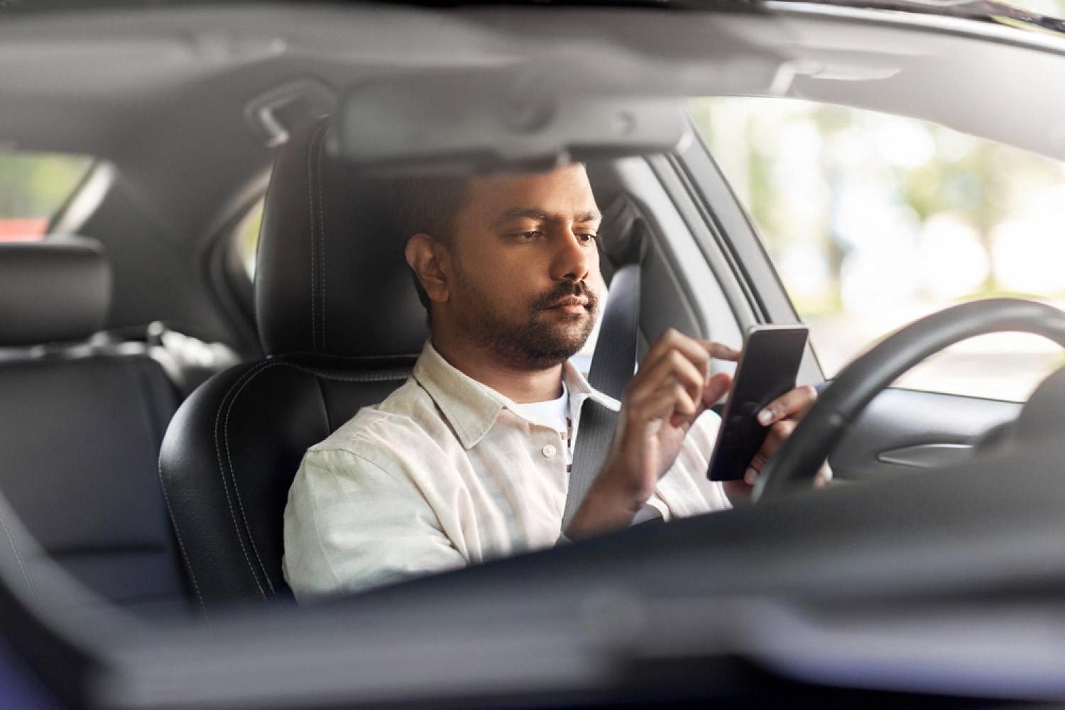 Driver using a smartphone inside a rental car to confirm an online booking